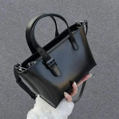 Black leather tote handbag for women with shoulder straps, casual design.