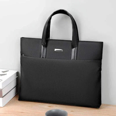 Sleek black laptop tote bag made of polyester with sturdy handles on a desk.