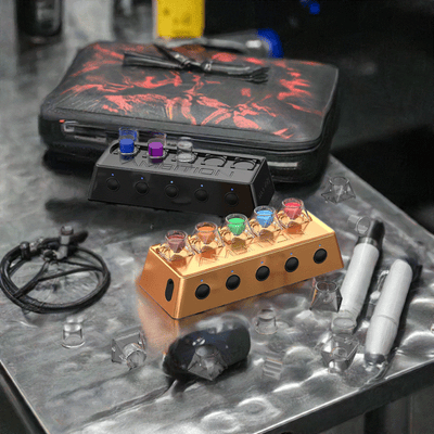 Ambition A1 Ink Mixer in gold and black on artistic workspace with accessories.